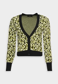 Cardigan à motifs avec un col en V profond, des manches longues et une bordure noire. Le tissu présente un motif floral jaune sur un fond noir.
