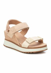 Sandalias de cuña beige con correas ajustables duales, acentos texturizados y una suela de goma blanca. Cuentan con una parte superior de cuero suave y una plantilla acolchada.