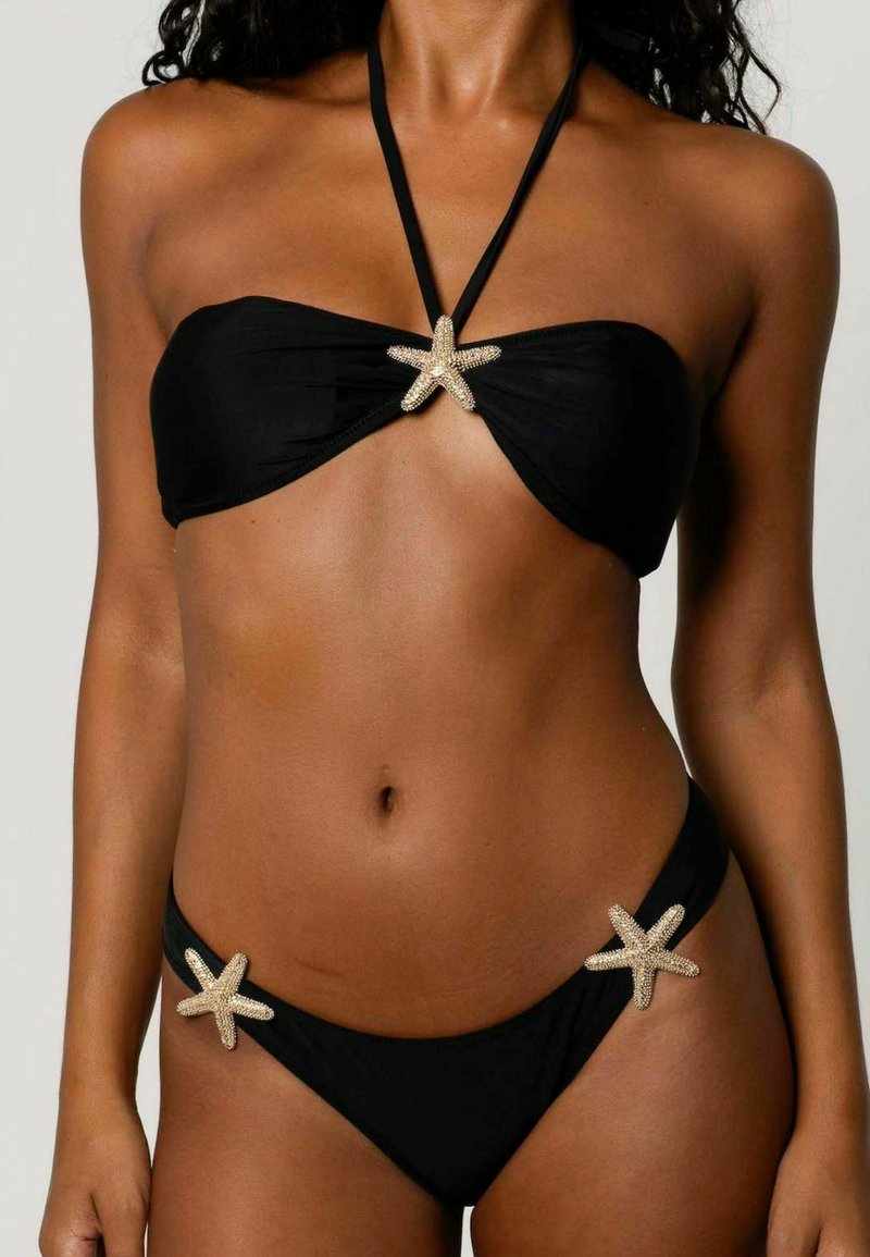 Schwarzes Bikini-Set mit einem Bandeau-Oberteil, das mit einer zentralen goldenen Seestern-Applikation versehen ist, sowie einem passenden Unterteil mit Seestern-Akzenten an den Seiten.