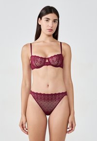 Bordowy zestaw koronkowy: biustonosz i stringi, z przezroczystego materiału, z kwiatowymi wzorami, regulowanymi ramiączkami i falbaniastymi brzegami.