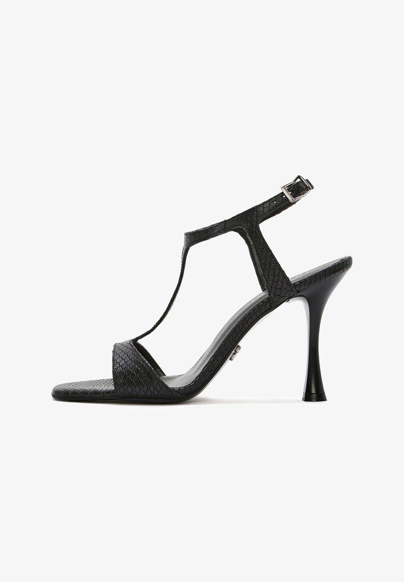 Sandale noire à talons hauts avec un motif reptilien texturé, design en T, boucle en métal argenté et bout pointu élégant.