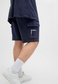 Navy Cargo-Shorts mit Seitentaschen, ausgestattet mit einem "Jack & Jones" Logo in Weiß und Rot. Hergestellt aus Baumwolle wirkt der Stoff weich und bequem.