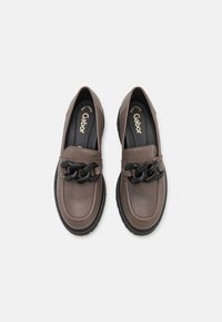 Brown leather slip-on shoes with a black chain accent and sturdy rubber sole. Smooth texture, rounded toe, and minimal detailing.