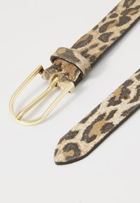 Opasek s leopardím potiskem vyrobený z měkké zvláštní kůže s kovovou sponou ve zlaté barvě. Má černobéžový vzor s hladkým povrchem a zúženým koncem.