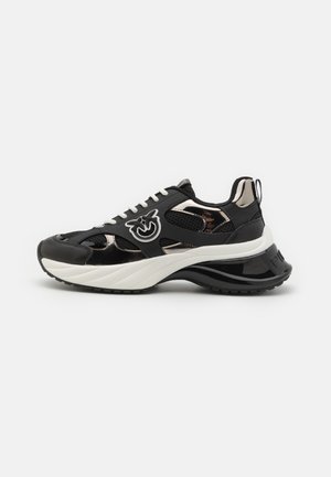 Sneakers sportivi neri con sovrapposizioni in rete e sintetico, una suola intermedia spessa bianca e una suola esterna nera lucida. Logo ben visibile sul lato.