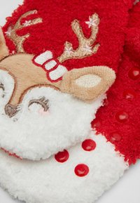 Calzini rossi e bianchi soffici con un motivo di renna, caratterizzati da corna ricamate, consistenza morbida e dettagli a pois rossi sulla zona bianca.