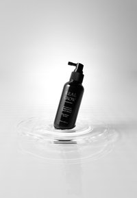 Schwarze Flasche mit Pumpe, ausgestattet mit einem schlanken Design und mattem Finish. Auf der Vorderseite steht "REAL GROW" und Produktdetails.