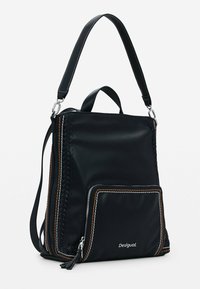 Czarny skórzany plecak z przednią kieszenią na zamek, plecionymi bocznymi detalami oraz białym i pomarańczowym przeszyciem, wyposażony w górny uchwyt i regulowane paski.