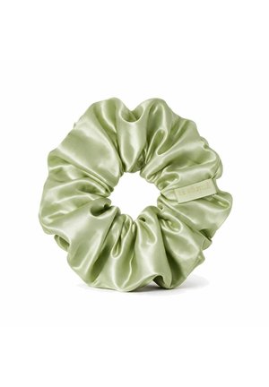 Hellgrünes Satin-Haargummi mit einem kleinen Stoffetikett auf weißem Hintergrund.