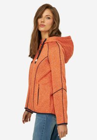 Giacca in fleece arancione con cappuccio, caratterizzata da cuciture di accentuazione nere, zip e una finitura testurizzata. Disponibile in una vestibilità comoda.