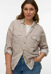 Gestreept shirt in beige en wit, met twee borstzakken en bruine knopen. De mouwen zijn opgerold en de stof heeft een zachte textuur.