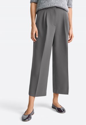 Woman wearing high-waisted, wide-leg gray trousers paired with a gray knit sweater and metallic gray ballet flats, standing on white background.