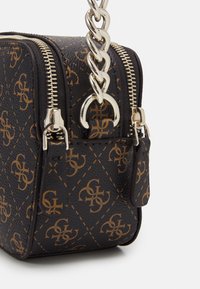 Borsa a mano in pelle nera con hardware dorato, caratterizzata da un motivo monogramma distintivo e chiusura con zip. Include una tracolla a catena e dettaglio laterale.