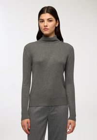 Maglione a collo alto grigio in cotone con texture a coste, maniche lunghe e design aderente; abbinato a pantaloni a righe grigie chiaro.
