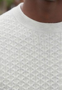 Pull en maille gris clair avec un motif texturé et des formes géométriques en relief, et un col côtelé. Fabriqué dans un matériau doux et confortable.