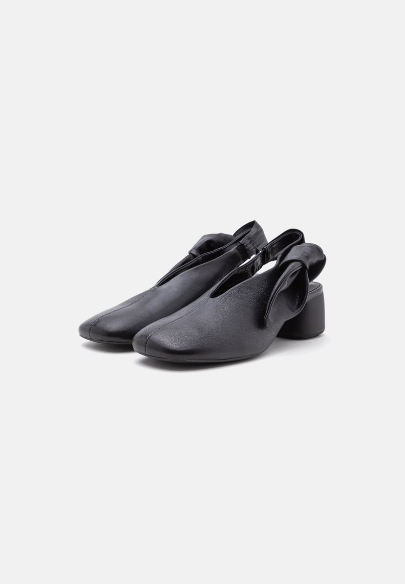 Paar schwarze Leder Slingback-Schuhe mit niedrigem Absatz und gefaltetem Detail an den Seiten, vor weißem Hintergrund gezeigt.