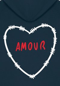 Felpa blu navy con una sagoma di cuore cucita in bianco e la parola "AMOUR" in grassetto rosso, che mette in risalto la texture del tessuto e i dettagli del ricamo.