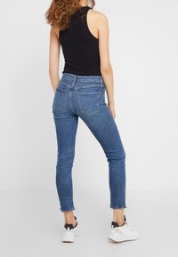 Smala jeans i medelblå denim, med hög midja, bakfickor och en blekt utseende. Tillsammans med vita sportskor.