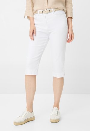 Weiße Baumwoll-Bermudashorts mit geradem Schnitt, umgeschlagenem Saum und Gürtelschlaufen, kombiniert mit hellen Schnürschuhen.