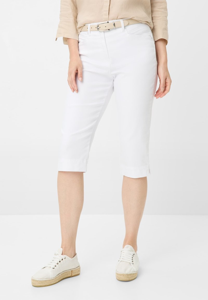 Bermuda shorts bianchi in cotone con taglio dritto, orlo piegato e passanti per cintura, abbinati a scarpe stringate di colore chiaro.