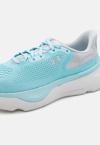 Jasnoniebieskie buty do biegania z siateczkową cholewką, teksturowanymi elementami i białą amortyzującą podeszwą. Posiadają wyraźne logo z boku oraz na sznurowadłach.