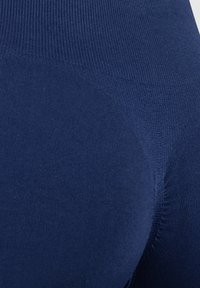 Navy modré punčocháče vyrobené z elastického materiálu. Mají hladký povrch a žebrovaný pas bez švů pro pohodlí a přiléhavost.