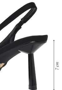 Zwart hooggehakte slingback met een naaldhak van 7 cm en een dunne enkelriem, voorzien van een kleine goudkleurige versiering nabij de zool.