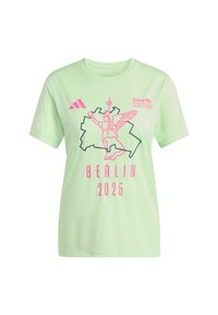 Vaaleanvihreä puuvillapaita, jossa on lyhyet hihat, jossa on vaaleanpunainen grafiikka siipisestä hahmosta ja teksti "BERLIN 2025", sekä Adidas-logo.