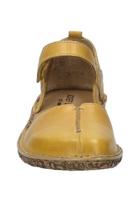 Zapato amarillo de cuero estilo Mary Jane con una correa de velcro, punta redonda y suela de goma texturizada. El interior cuenta con un forro suave.