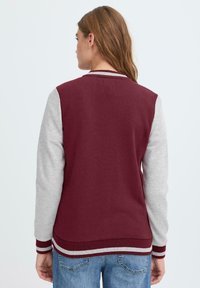 Bordeauxrød og grå sweatshirt med lange ærmer, ribbede manchetter og kant. Fremstillet af blødt stof; har et klassisk varsity-design.