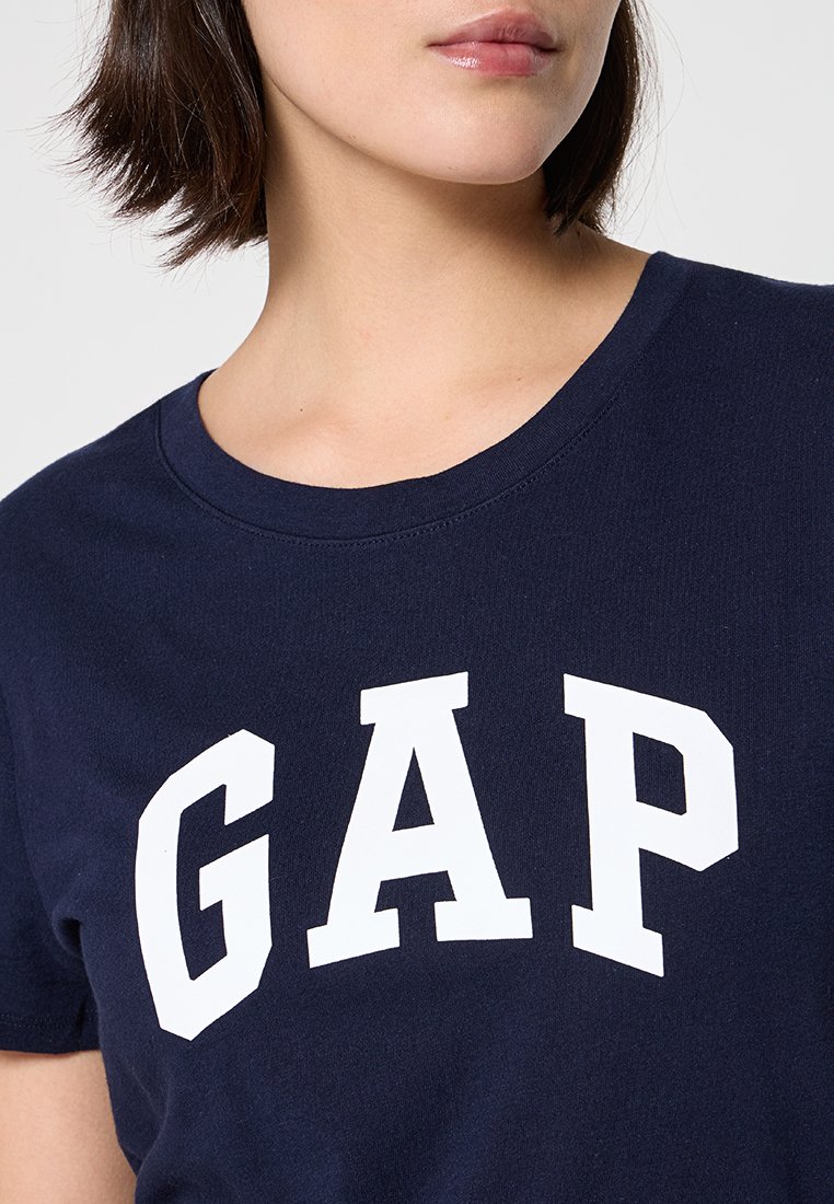 Marineblaue Baumwoll-T-Shirt mit Rundhalsauschnitt, verziert mit großen weißen Blockbuchstaben, die "GAP" auf der Brust schreiben.