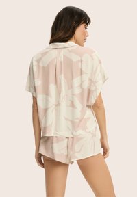 Krótki rękaw, jasnoróżowy zestaw piżamowy w kwiaty z luźną bluzką z kołnierzykiem oraz dopasowanymi szortami, wykonany z miękkiego materiału o gładkiej teksturze.
