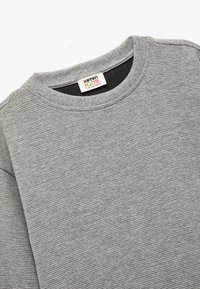 Grå långärmad sweatshirt med ribbat tyg och rund halsringning, med en "Kottan Kids"-tagg inuti kragen.