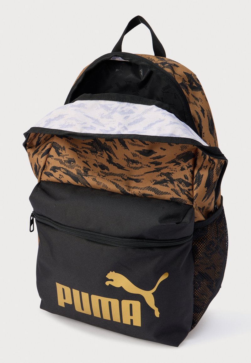 Sac à dos à motifs marron et noir avec poches à fermeture éclair, arborant un logo Puma doré, des détails en mesh et une doublure intérieure texturée.