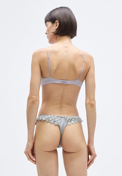 Világosszürke fehérnemű szett, amely selyem bralette-et tartalmaz vékony pántokkal, valamint egy hozzáillő, fodros szélű, texturált gyémántmintás tanga alsót.