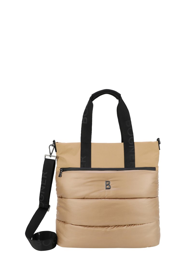 Vaalean beige-värinen pehmustettu kassi mustilla logohihnoilla, edessä vetoketjullinen tasku ja irrotettava olkahihna. Liukas pinta ja moderni muotoilu.