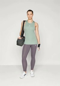 Top atlético sem mangas de cor verde claro, leggings cinzentas com riscas brancas, ténis brancos e uma mala de ginásio preta. Concebido para vestuário desportivo.