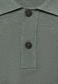Šedé texturované polo tričko s knoflíkovým límcem se dvěma černými knoflíky a vzorem tkaniny. Design zaměřený na detaily.