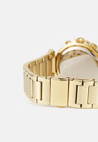 Orologio in metallo dorato con bracciale a maglie, caratterizzato da una finitura lucida, cassa rotonda e una corona visibile. Non ci sono dettagli visibili sul quadrante.