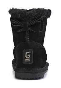 Svarta mocka ankestövlar med en fluffig, pälsfoder krage, en rosettdetalj på baksidan och en gummisula med ett varumärke.