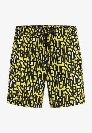 Bañadores negros y amarillos con un patrón gráfico de texto, cinturilla elástica con cordón y parche de logo en la parte inferior izquierda.