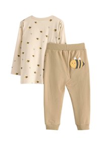 To-delt børnetøj; langærmet cremetop med sort og gul bi-print og beige bukser med en bi-appliqué på ryggen.