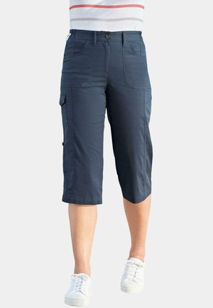 Pantalons capri cargo marine en tissu durable, dotés de poches latérales, d'une fermeture à bouton et d'une coupe décontractée. Associés avec des baskets blanches.