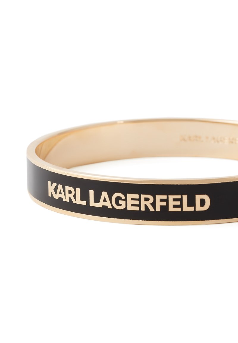 Bracelet jonc doré avec incrustation en émail noir arborant le texte du logo "KARL LAGERFELD" en lettres dorées.