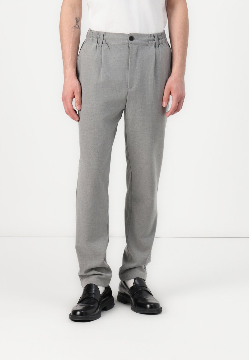 Lichtgrijze broek met een ontspannen pasvorm, voorzien van een elastische tailleband en een enkele knoopsluiting. Glad textuur, minimalistisch ontwerp.
