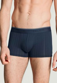 Marineblauwe boxershorts met verticale strepen, gemaakt van zacht materiaal. Heeft een Calida-logo op de tailleband en een aansluitend ontwerp.