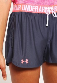 Námořnické modré sportovní šortky s pružným pasem v růžové barvě "Under Armour", které mají šňůrku na stažení a malé růžové logo na dolním lemu.