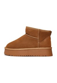 Bottines en daim marron avec un bout rond, un design de hauteur moyenne, un accent de couture ton sur ton et une semelle en caoutchouc épaisse. Texture lisse.