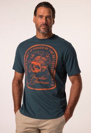 T-shirt couleur bleu canard avec des manches courtes, présentant un design graphique orange d'un crâne et du texte indiquant "Marin intrépide". Texture lisse.