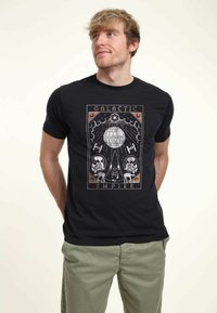 Černé bavlněné tričko s grafickým designem Hvězdy smrti, stormtrooperů a Darth Vadera, označené "Galaktické impérium." Krátké rukávy.